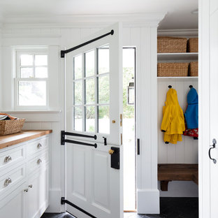 ニューヨークのダッチドアトラディショナルスタイルのおしゃれなマッドルーム (白い壁、スレートの床、白いドア、黒い床) の写真