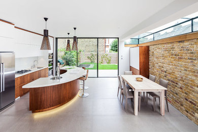 Photo of a large contemporary galley eat-in kitchen in London with an undermount sink, flat-panel cabinets, medium wood cabinets, white splashback, stainless steel appliances and with island.