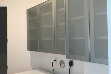 Inspiration for a mid-sized contemporary dedicated laundry room remodel in Miami with white walls and a stacked washer/dryer