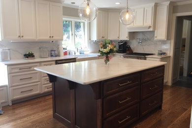 Eat-in kitchen - mid-sized transitional l-shaped dark wood floor and brown floor eat-in kitchen idea in Orange County with a farmhouse sink, recessed-panel cabinets, white cabinets, marble countertops, white backsplash, stone slab backsplash, an island and white countertops