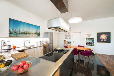 This is an example of an expansive industrial u-shaped eat-in kitchen in Munich with an integrated sink, stainless steel cabinets, white splashback, stainless steel appliances, no island and stainless steel benchtops.