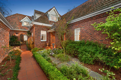 This is an example of a mid-sized traditional garden in Melbourne with a garden path and natural stone pavers.