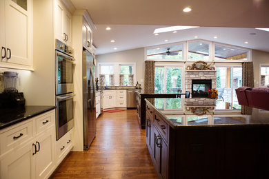 Inspiration for an expansive traditional u-shaped eat-in kitchen in St Louis with flat-panel cabinets, granite benchtops, stone tile splashback, stainless steel appliances and multiple islands.