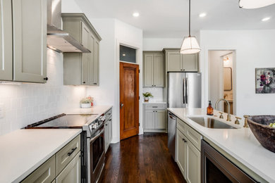 Medium tone wood floor and brown floor kitchen photo in Other with an undermount sink, shaker cabinets, green cabinets, quartz countertops, white backsplash, porcelain backsplash, stainless steel appliances and white countertops