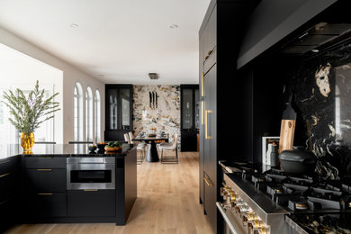 Inspiration for a mid-sized modern u-shaped kitchen in Other with an undermount sink, flat-panel cabinets, black cabinets, granite benchtops, black splashback, granite splashback, stainless steel appliances, light hardwood floors, a peninsula, brown floor and black benchtop.