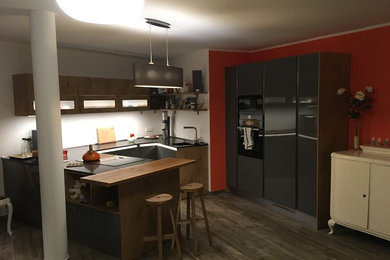 Große Moderne Wohnküche in U-Form mit integriertem Waschbecken, flächenbündigen Schrankfronten, grauen Schränken, Quarzwerkstein-Arbeitsplatte, schwarzen Elektrogeräten und Halbinsel in Sonstige