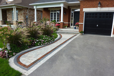 Photo of a full sun front yard concrete paver driveway in Toronto.