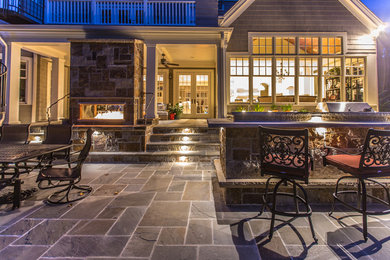 This is an example of a large arts and crafts backyard patio in Charlotte with a fire feature and natural stone pavers.