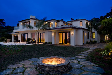 Large island style white two-story stucco house exterior photo in Santa Barbara with a hip roof and a shingle roof