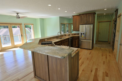 Inspiration for a mid-sized craftsman single-wall light wood floor open concept kitchen remodel in Milwaukee with an undermount sink, recessed-panel cabinets, brown cabinets, quartzite countertops, brown backsplash, stone slab backsplash and stainless steel appliances