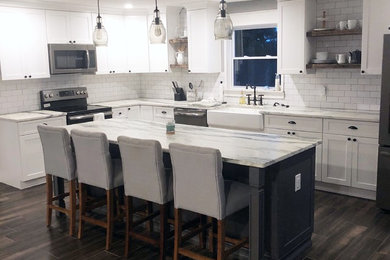 Large country l-shaped porcelain tile and brown floor open concept kitchen photo in Tampa with a farmhouse sink, shaker cabinets, white cabinets, marble countertops, white backsplash, subway tile backsplash, stainless steel appliances, an island and white countertops