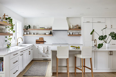 Large transitional l-shaped light wood floor eat-in kitchen photo in DC Metro with white cabinets, white backsplash, paneled appliances and an island
