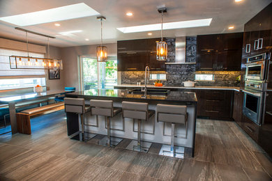 Trendy l-shaped vinyl floor open concept kitchen photo in Other with a drop-in sink, flat-panel cabinets, brown cabinets, quartz countertops, gray backsplash, stone slab backsplash, stainless steel appliances and an island