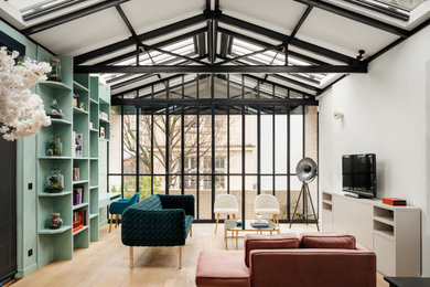 Moderne Bibliothek mit weißer Wandfarbe, hellem Holzboden, freistehendem TV, beigem Boden und freigelegten Dachbalken in Paris