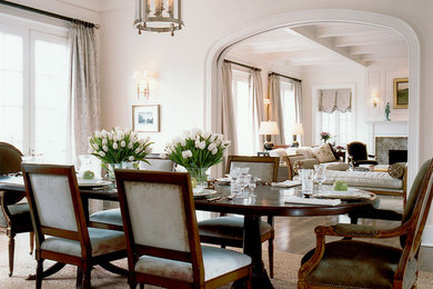 Example of a classic medium tone wood floor dining room design in DC Metro with white walls, a standard fireplace and a stone fireplace