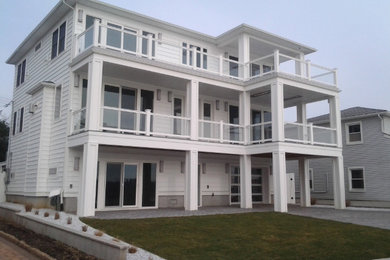 Imagen de fachada de casa blanca minimalista grande de tres plantas con revestimiento de vinilo, tejado a dos aguas y tejado de teja de madera