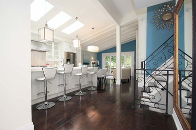 Mid-sized trendy galley dark wood floor and brown floor open concept kitchen photo in Toronto with recessed-panel cabinets, solid surface countertops, an island, an undermount sink, blue cabinets, stone tile backsplash, beige backsplash and stainless steel appliances