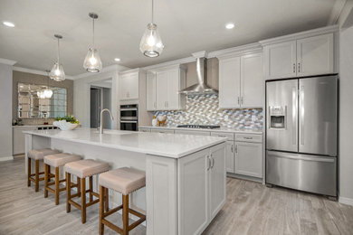 Open concept kitchen - coastal vinyl floor and gray floor open concept kitchen idea in Jacksonville with gray cabinets, quartz countertops, multicolored backsplash, mosaic tile backsplash, stainless steel appliances, an island, white countertops, an undermount sink and recessed-panel cabinets