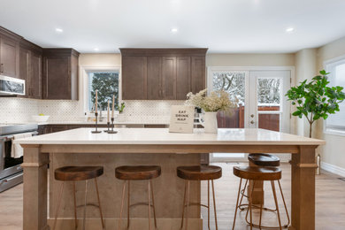 Example of a mid-sized transitional u-shaped vinyl floor and beige floor eat-in kitchen design in Ottawa with an island, an undermount sink, shaker cabinets, medium tone wood cabinets, quartz countertops, gray backsplash, ceramic backsplash, stainless steel appliances and white countertops