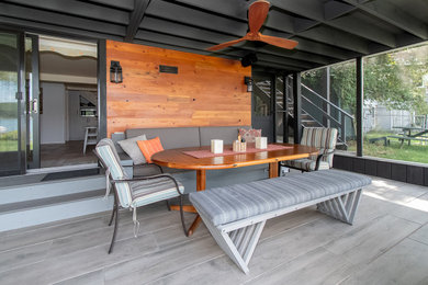 Inspiration for a large modern stone screened-in front porch remodel in New York with a roof extension