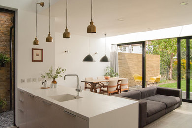 Photo of a contemporary kitchen in London with an integrated sink, flat-panel cabinets and a peninsula.