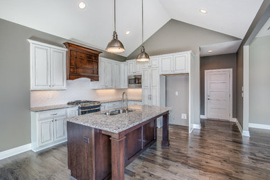 Example of a mid-sized transitional l-shaped dark wood floor eat-in kitchen design in Wichita with an undermount sink, raised-panel cabinets, granite countertops, stainless steel appliances and an island