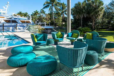 Patio - large modern side yard stone patio idea in Miami with a roof extension