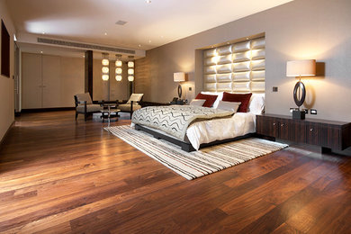 Photo of an expansive contemporary loft-style bedroom in London with beige walls and medium hardwood floors.
