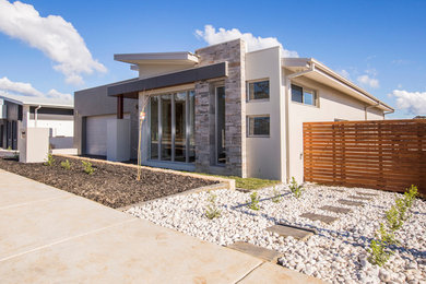 This is an example of a mid-sized one-storey concrete grey house exterior in Canberra - Queanbeyan with a flat roof and a metal roof.