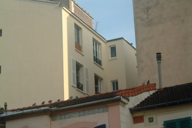 Medium sized and beige classic concrete terraced house in Paris with three floors, a mansard roof and a tiled roof.