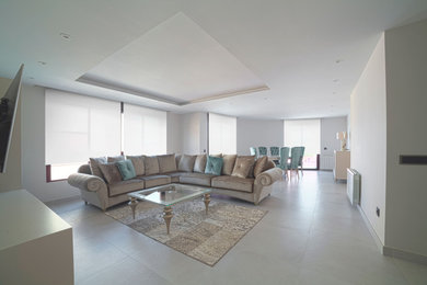 Ejemplo de salón cerrado actual grande con paredes beige, suelo de baldosas de porcelana, televisor colgado en la pared y suelo beige