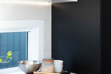Inspiration for a mid-sized contemporary galley eat-in kitchen in Brisbane with an undermount sink, shaker cabinets, black cabinets, quartzite benchtops, white splashback, ceramic splashback, stainless steel appliances, light hardwood floors, with island and white benchtop.