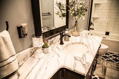 Example of a mid-sized transitional 3/4 white tile and subway tile porcelain tile and gray floor bathroom design in New York with recessed-panel cabinets, dark wood cabinets, a two-piece toilet, gray walls, an undermount sink, marble countertops, a hinged shower door and white countertops