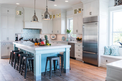 Inspiration for a mid-sized beach style l-shaped open plan kitchen in Miami with an undermount sink, shaker cabinets, white cabinets, marble benchtops, white splashback, subway tile splashback, stainless steel appliances, dark hardwood floors and with island.