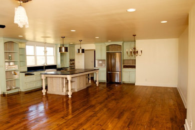 Large country medium tone wood floor eat-in kitchen photo in Other with a farmhouse sink, recessed-panel cabinets, distressed cabinets, black backsplash, stainless steel appliances and an island