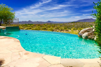 Inspiration for a large southwestern backyard stamped concrete and custom-shaped infinity hot tub remodel in Phoenix