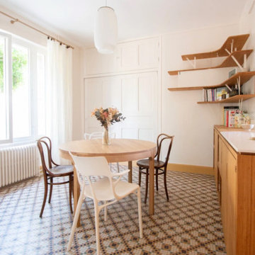 Espace salle à manger avec sa table en bois circulaire et sa suspension blanche