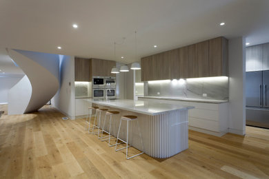 Photo of a large modern kitchen pantry in Melbourne with flat-panel cabinets, distressed cabinets, quartzite benchtops, white appliances and with island.