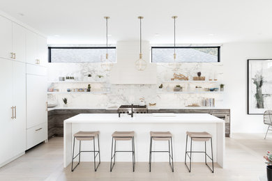 Example of a large danish l-shaped light wood floor and white floor open concept kitchen design in Toronto with an undermount sink, flat-panel cabinets, distressed cabinets, quartz countertops, white backsplash, marble backsplash, paneled appliances, an island and white countertops