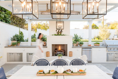 Inspiration for a mid-sized coastal backyard stone patio remodel in Orange County with a fireplace and a gazebo