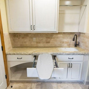 オレンジカウンティの中サイズのラスティックスタイルのおしゃれな家事室 (アンダーカウンターシンク、白いキャビネット、御影石カウンター、黄色い壁、トラバーチンの床、ベージュの床、落し込みパネル扉のキャビネット) の写真