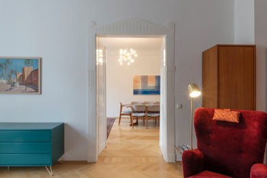 Mittelgroßes, Fernseherloses Wohnzimmer mit braunem Holzboden und weißer Wandfarbe in München