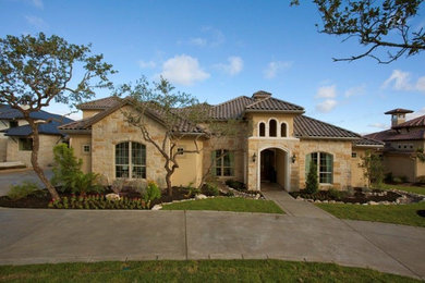 Large transitional beige two-story stone exterior home idea in Austin with a hip roof
