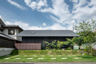 Foto de fachada de casa negra y negra de una planta con tejado a dos aguas y tejado de metal