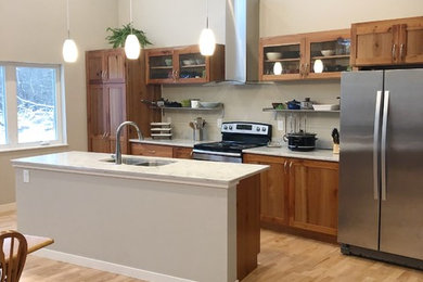 Inspiration for a large eclectic galley medium tone wood floor and brown floor eat-in kitchen remodel in Other with a drop-in sink, shaker cabinets, brown cabinets, granite countertops, white backsplash, ceramic backsplash, stainless steel appliances, an island and white countertops