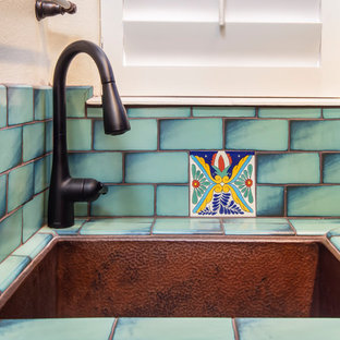 ロサンゼルスの大きいサンタフェスタイルのおしゃれな洗濯室 (アンダーカウンターシンク、レイズドパネル扉のキャビネット、青いキャビネット、クオーツストーンカウンター、白い壁、テラコッタタイルの床、左右配置の洗濯機・乾燥機、オレンジの床、黒いキッチンカウンター) の写真