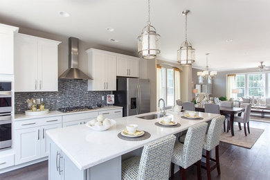 Inspiration for a large transitional medium tone wood floor open concept kitchen remodel in Raleigh with an undermount sink, shaker cabinets, white cabinets, multicolored backsplash, matchstick tile backsplash, stainless steel appliances and an island