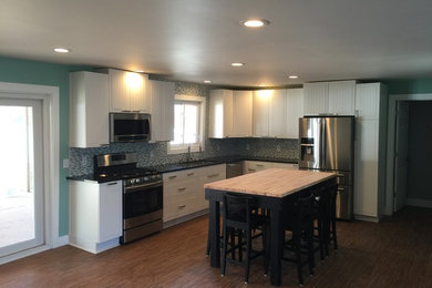 Example of a mid-sized trendy l-shaped dark wood floor kitchen design in Other with an undermount sink, louvered cabinets, white cabinets, solid surface countertops, multicolored backsplash, matchstick tile backsplash, stainless steel appliances and an island