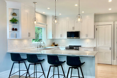 Mid-sized transitional u-shaped light wood floor and beige floor open concept kitchen photo in Other with an undermount sink, beaded inset cabinets, white cabinets, quartz countertops, white backsplash, ceramic backsplash, stainless steel appliances, a peninsula and white countertops
