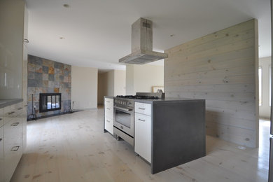 Inspiration for a mid-sized modern galley light wood floor and beige floor open concept kitchen remodel in Boston with flat-panel cabinets, white cabinets, beige backsplash, wood backsplash, stainless steel appliances and an island